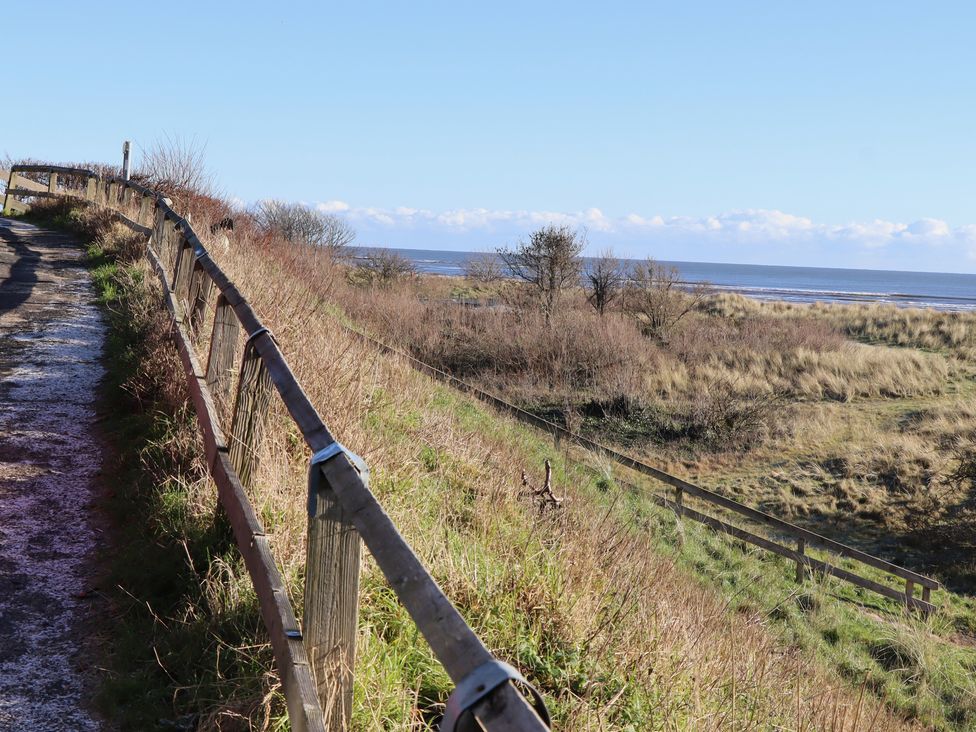 A path along a seaside with a fence and grass at Seafield Granary in Alnmouth