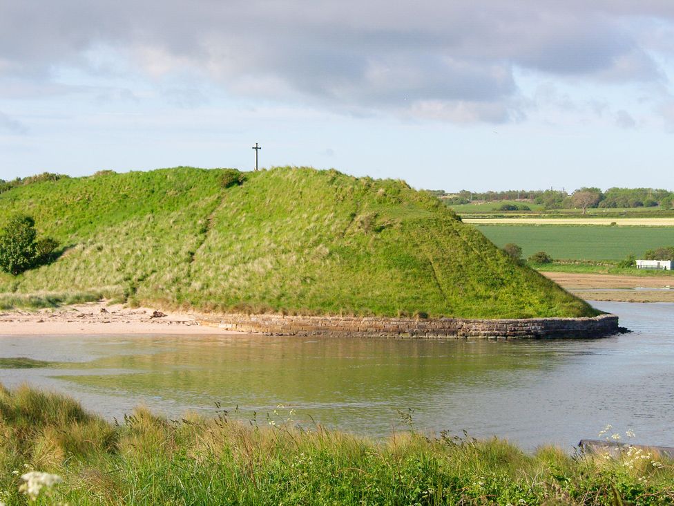 A hill near water with grass at Seafield Coach House in Alnmouth