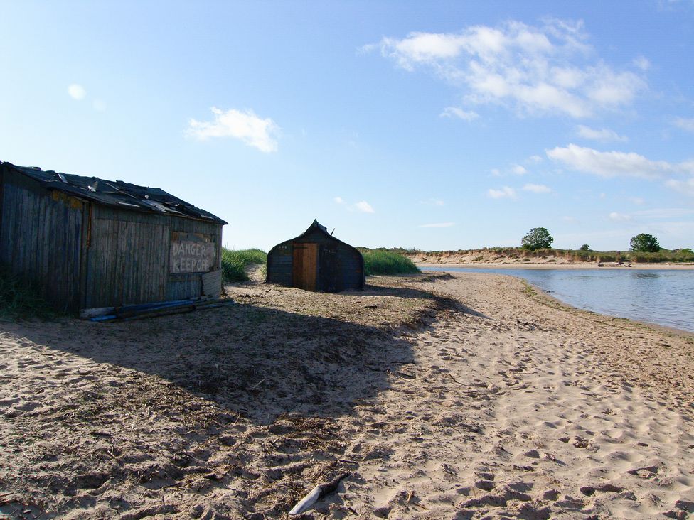 Two wooden huts on a beach near water at Seafield Coach House in Alnmouth