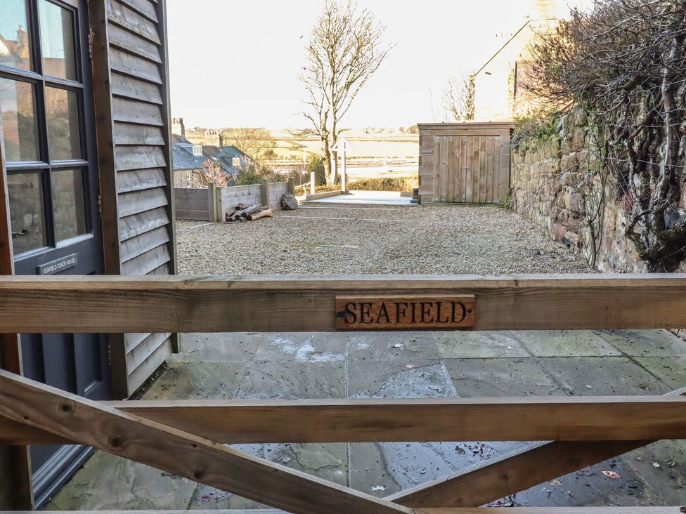 A view of a gravel pathway with a wooden gate at Seafield Coach House in Alnmouth