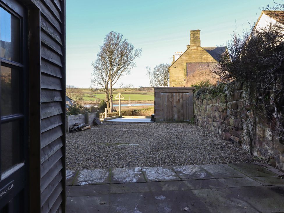 A garden view with a tree and gravel area at Seafield Coach House in Alnmouth