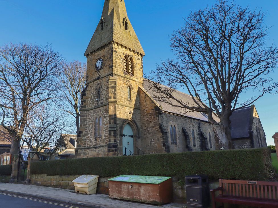 A church with a clock tower and benches at Seafield Coach House in Alnmouth