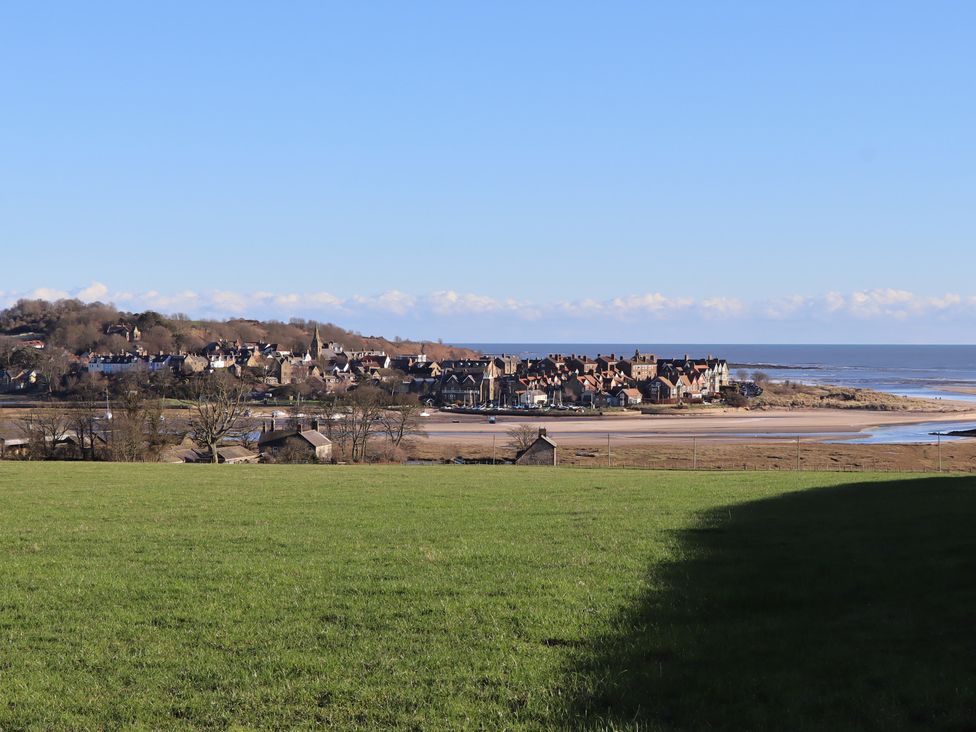 A view of a coastal area with buildings and water at Seafield Coach House in Alnmouth