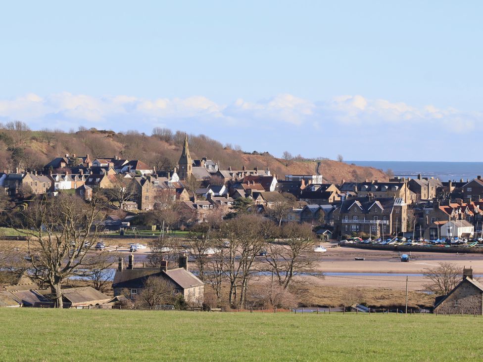 A view of a village with houses and a river at Seafield Coach House Alnmouth