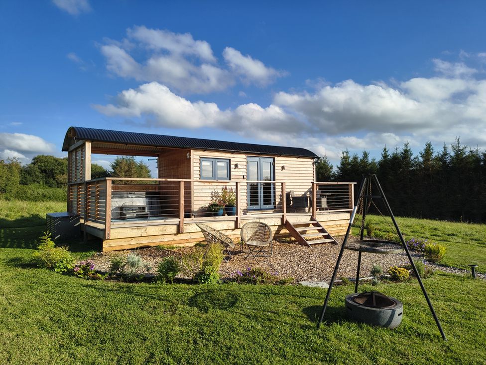 An outdoor area with a shepherd's hut and deck at Fir Tree Shepherd's Hut, Llanon