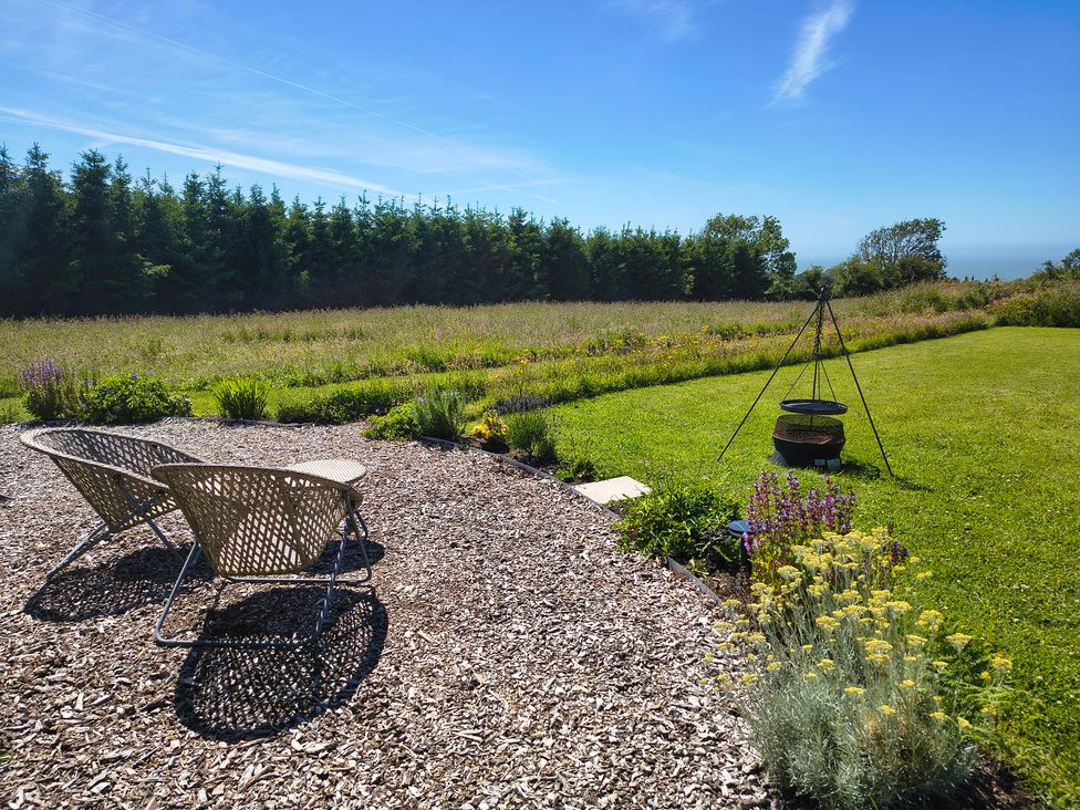 A garden with chairs and a fire pit at Fir Tree Shepherd's Hut in Llanon