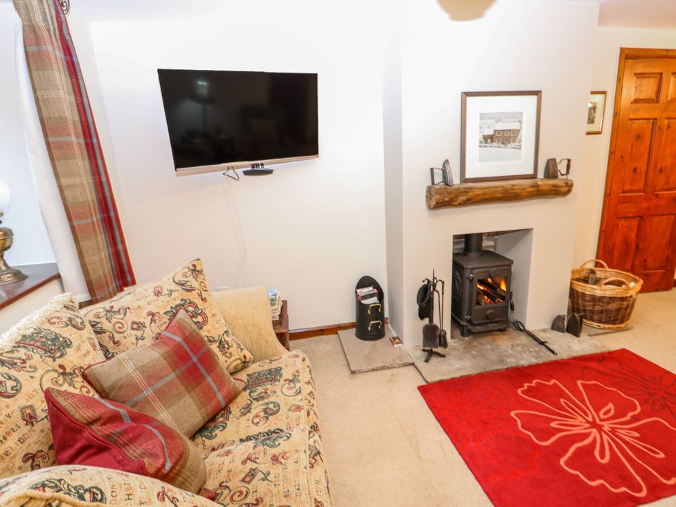 A living room with a television and a fireplace at Coldbeck Cottage in Ravenstonedale