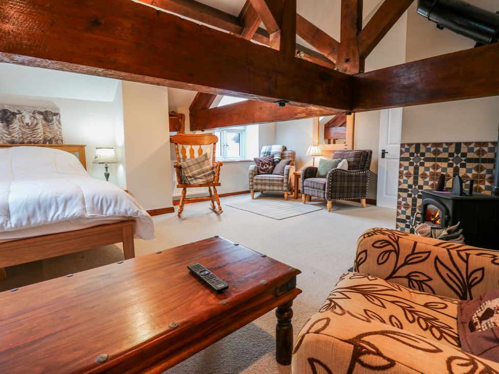 A bedroom with a bed, chairs, and a coffee table at Coldbeck Cottage Ravenstonedale