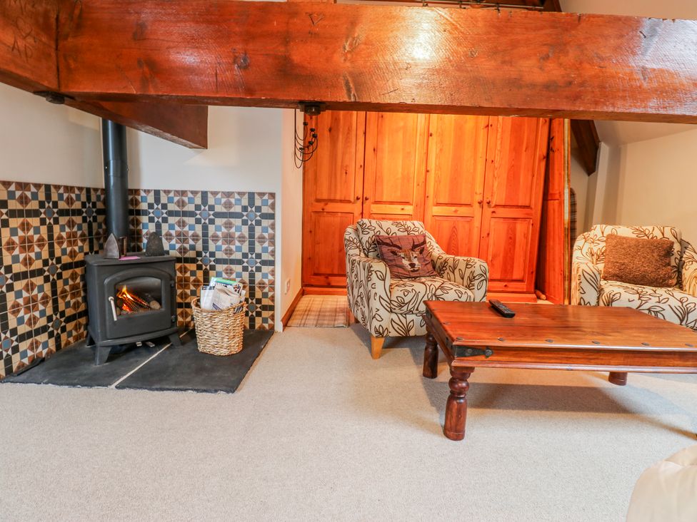 A living room with a fireplace and two armchairs at Coldbeck Cottage in Ravenstonedale