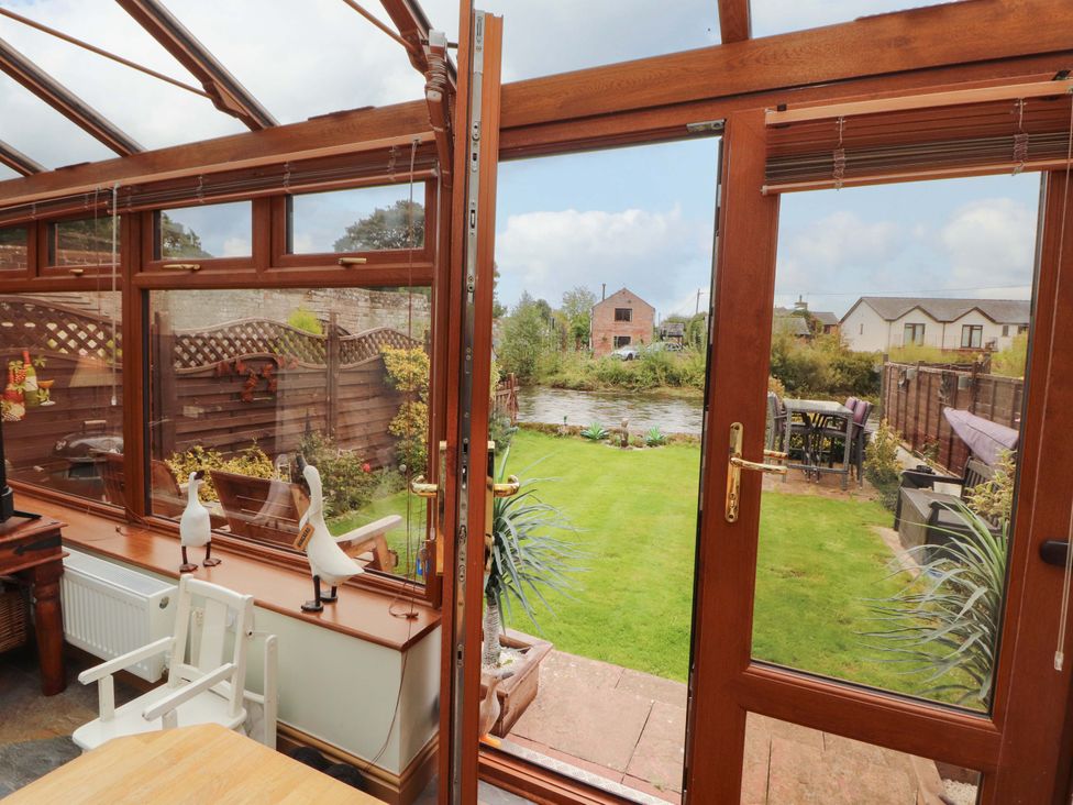 A conservatory with glass doors viewing a garden at Beckside Cottage Penrith