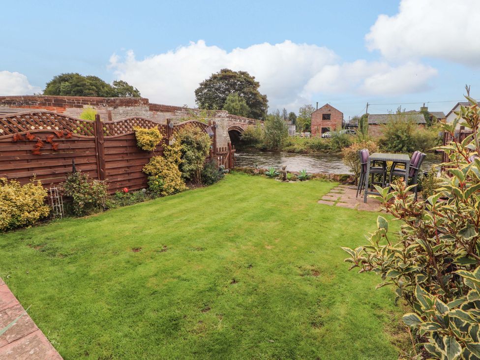 A garden with grass, fence, table, and chairs at Beckside Cottage, Penrith