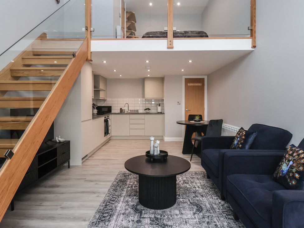 A living room with a staircase and kitchen area at Canal Side in Skipton