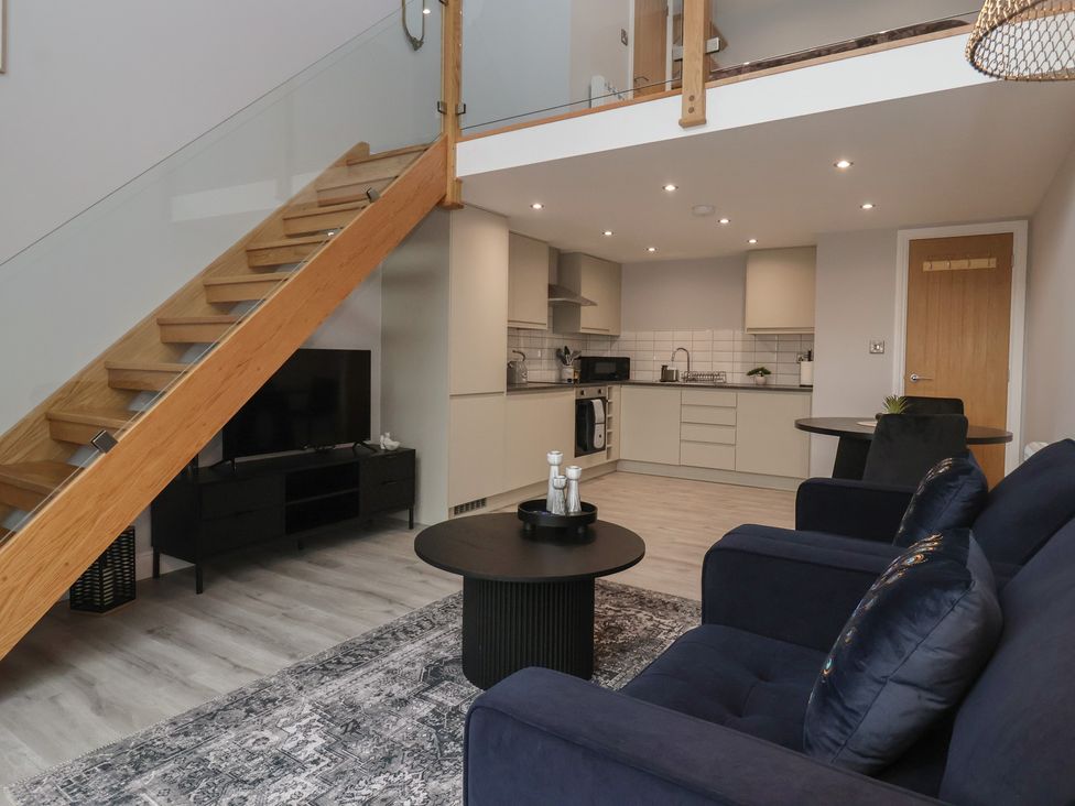 A living room with a sofa and kitchen area at Canal Side in Skipton