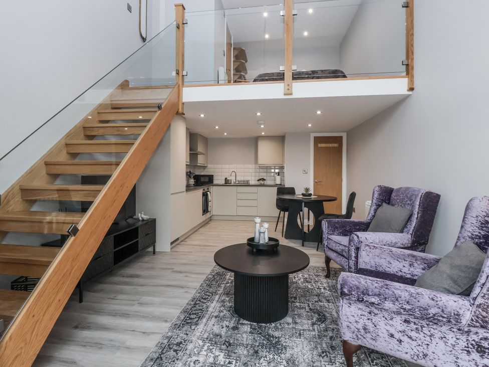 A living room with a staircase and kitchen area at Waters Edge in Skipton