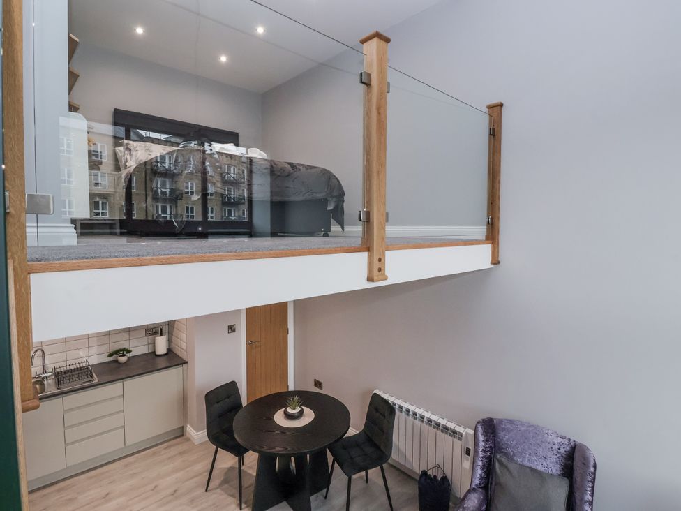 A living room with a bed on a mezzanine at Waters Edge Skipton