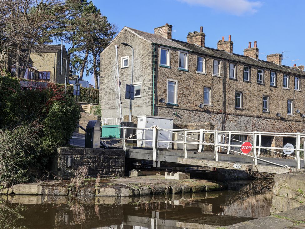 A building next to a canal with a bridge and stop sign at Waters Edge in Skipton