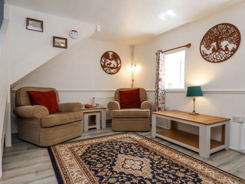 A sitting room with two armchairs a patterned rug a coffee table and wall decorations at Wayside Farm Dairy Cottage Cloughton near Burniston