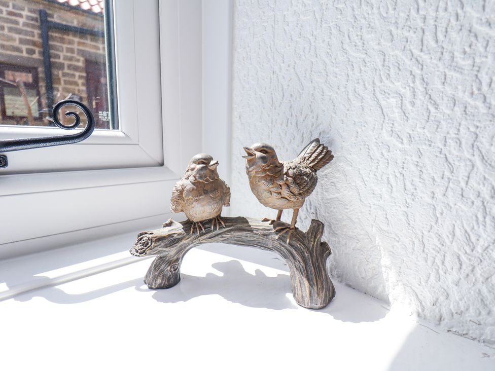 Two bird figurines perched on a branch decoration on a windowsill