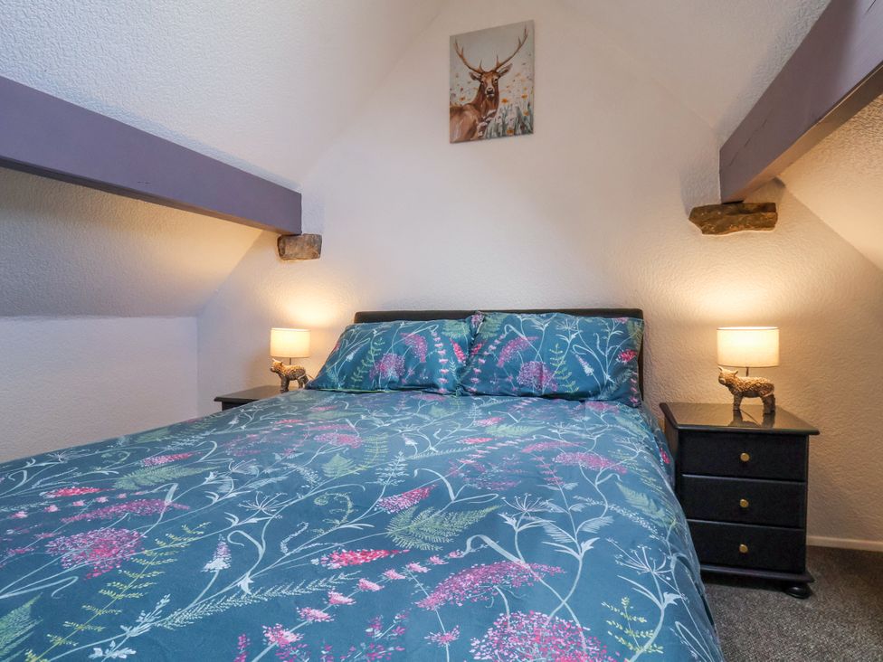 A bedroom with a bed and two bedside tables with lamps at Wayside Farm Dairy Cottage Cloughton near Burniston