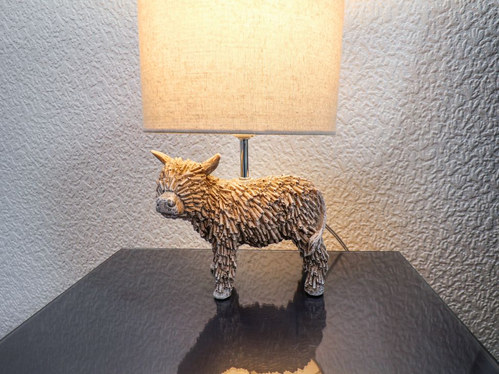 A lamp with a shade and a decorative sculpture of an animal on a reflective table surface