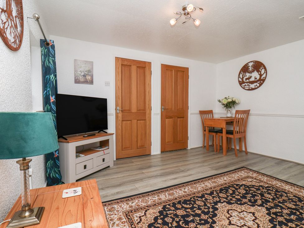 A living room with a television and dining table at Wayside Farm Dairy Cottage in Cloughton near Burniston