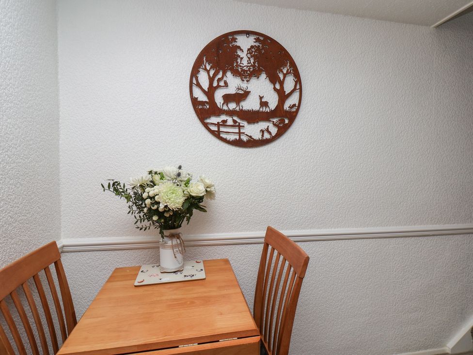 A dining area with a table and flower vase at Wayside Farm Dairy Cottage Cloughton near Burniston