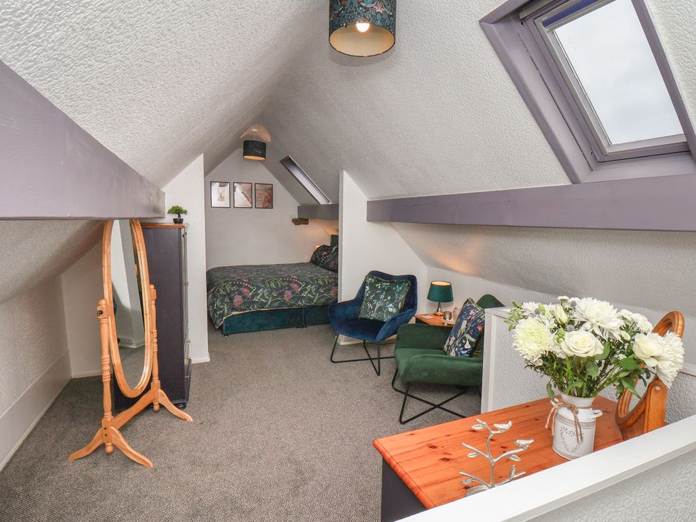 A bedroom with a bed and chairs at Wayside Farm Dairy Cottage in Cloughton near Burniston
