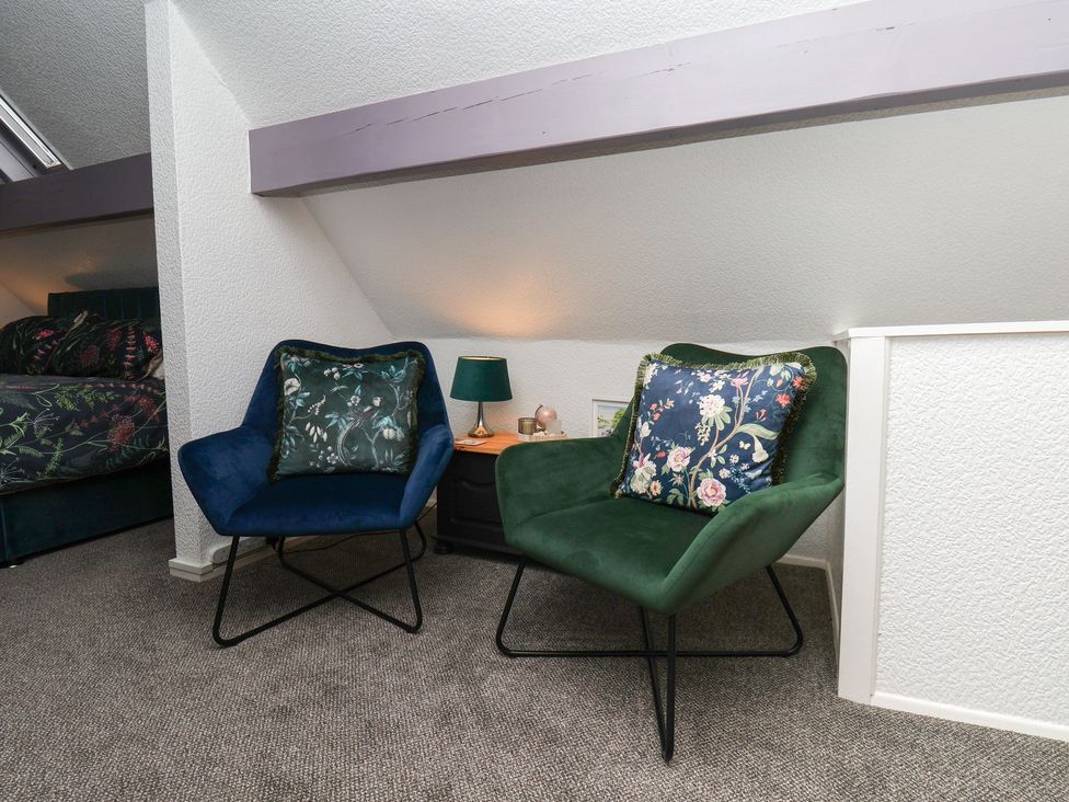 Two chairs and a bedside table in a bedroom at Wayside Farm Dairy Cottage in Cloughton near Burniston