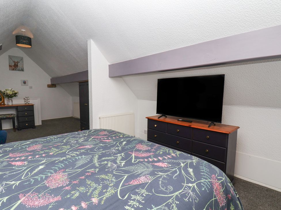 A bedroom with a bed, television, dresser and desk at Wayside Farm Dairy Cottage Cloughton near Burniston