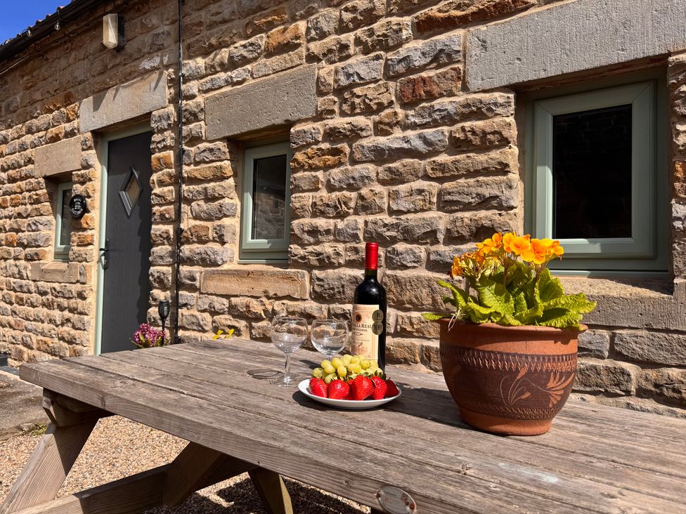 An outdoor table with wine and fruit at Wayside Farm Dairy Cottage in Cloughton near Burniston