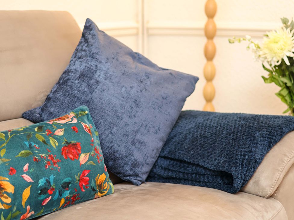 A couch with cushions and a blanket at Wayside Farm Dairy Cottage Cloughton near Burniston