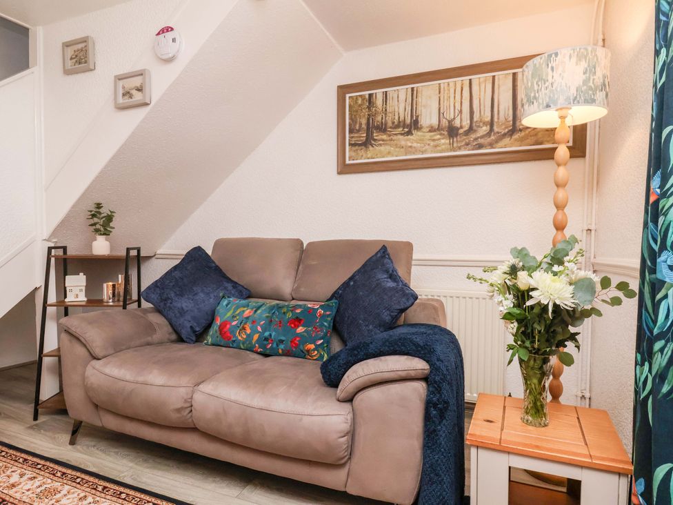 A living room featuring a sofa with cushions and a lamp at Wayside Farm Dairy Cottage Cloughton near Burniston
