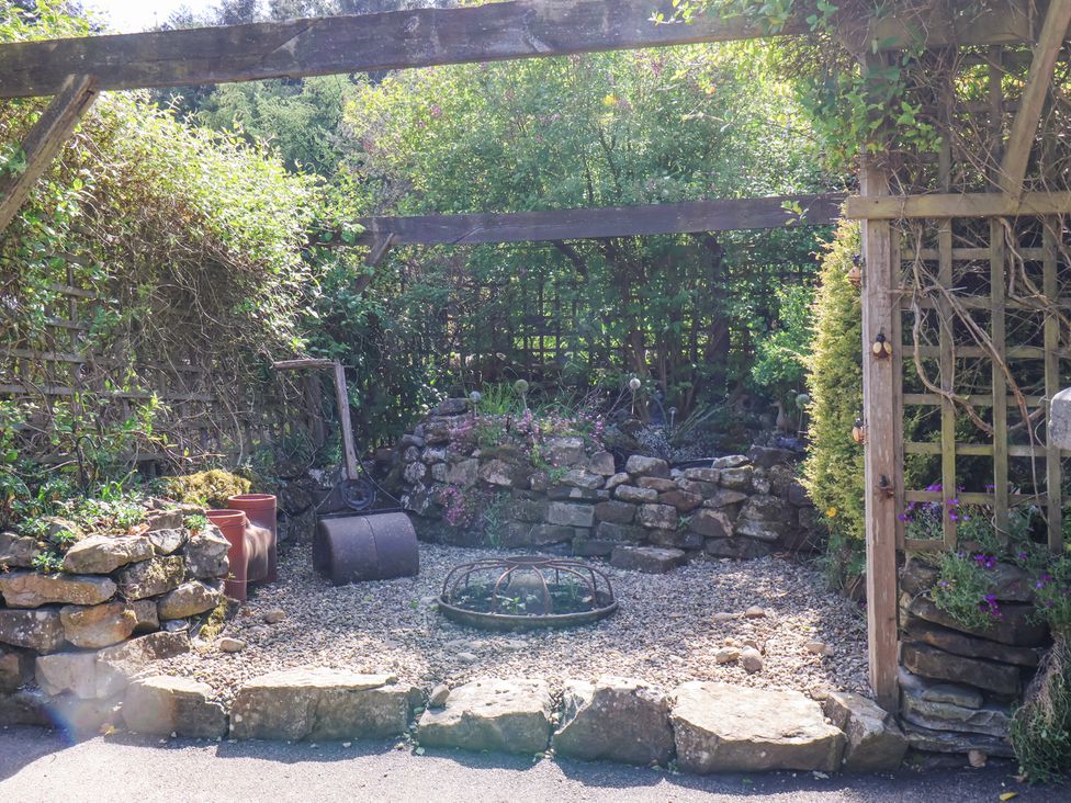A small garden area with stone walls gravel ground and plants at Wayside Farm Stable Cottage Cloughton near Burniston