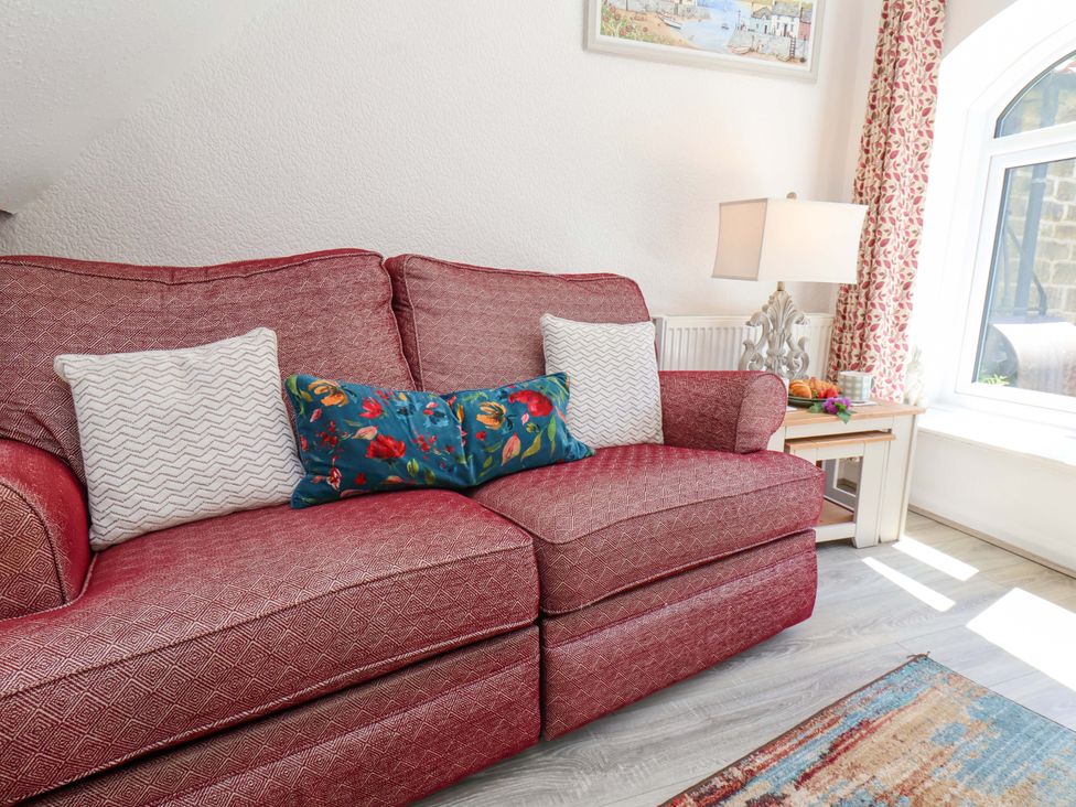 A living room with a sofa and decorative pillows at Wayside Farm Stable Cottage Cloughton near Burniston