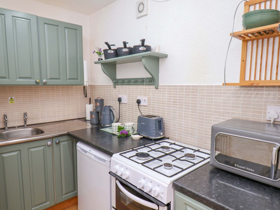 A kitchen with sink, cabinets, kettle, toaster, and microwave at Wayside Farm Stable Cottage Cloughton near Burniston
