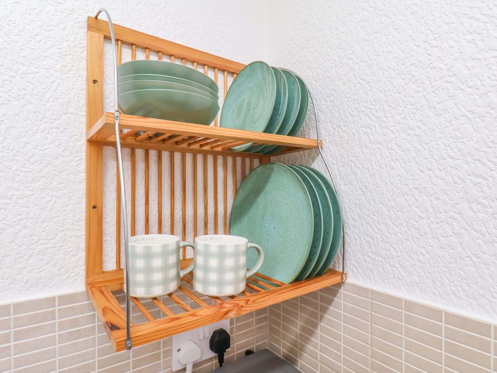 A shelf with plates and mugs at Wayside Farm Stable Cottage in Cloughton near Burniston