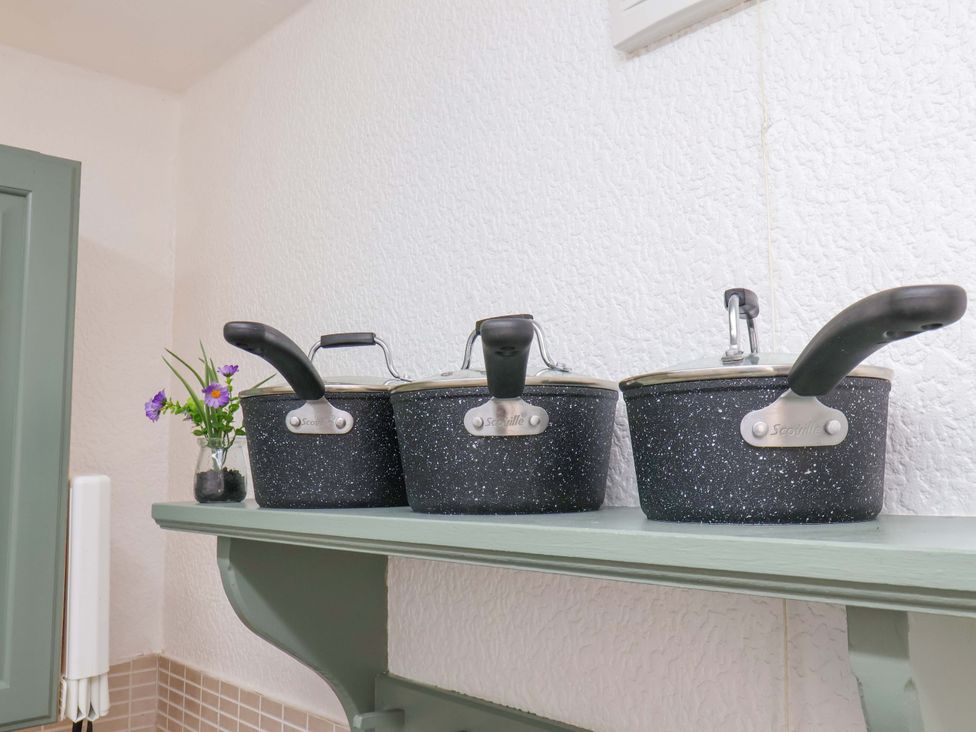 A shelf with three pans and a flower at Wayside Farm Stable Cottage in Cloughton near Burniston