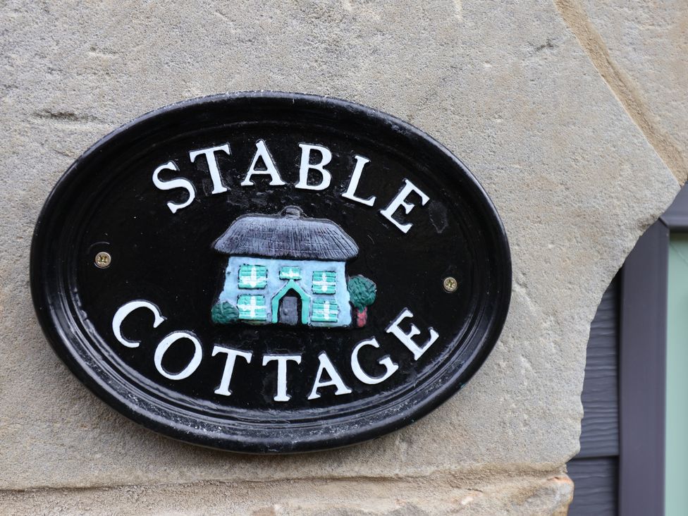 A sign reading 'Stable Cottage' on a stone wall at Wayside Farm Stable Cottage Cloughton near Burniston