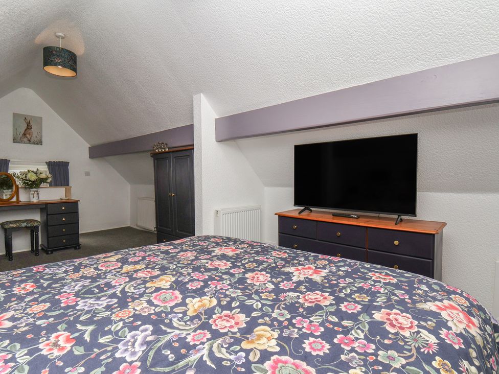 A bedroom with a bed, desk, chair, and television at Wayside Farm Stable Cottage Cloughton near Burniston