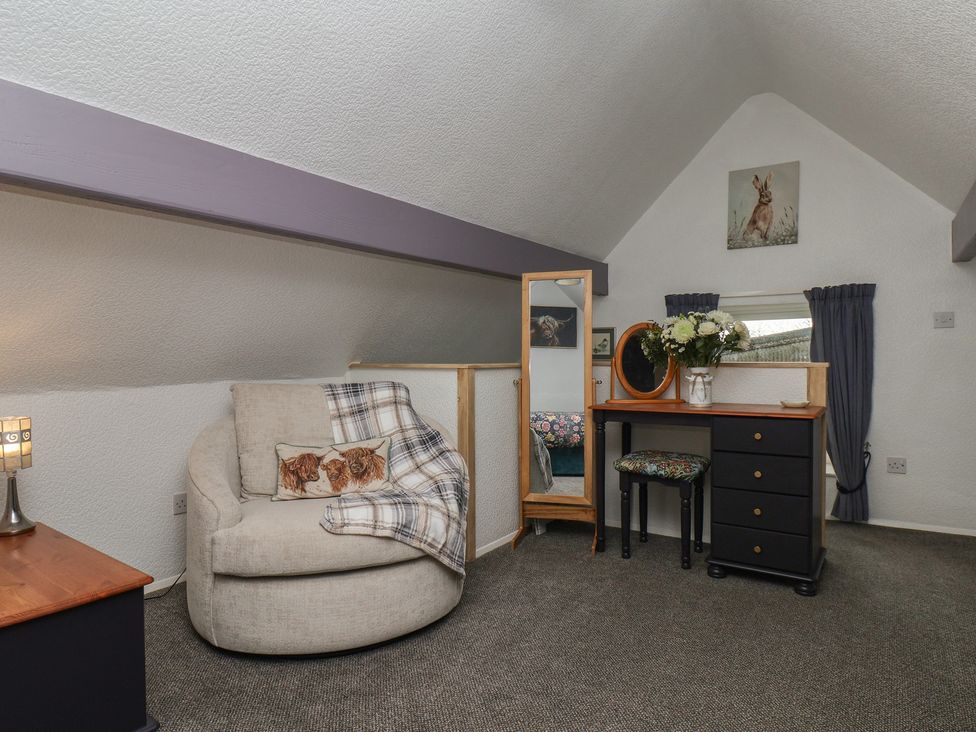 A bedroom with an armchair and dressing table at Wayside Farm Stable Cottage Cloughton near Burniston
