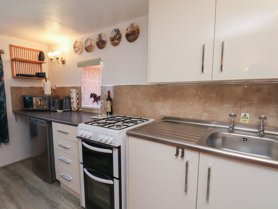 A kitchen with a stove and sink at Wayside Farm Cart Cottage in Cloughton near Burniston