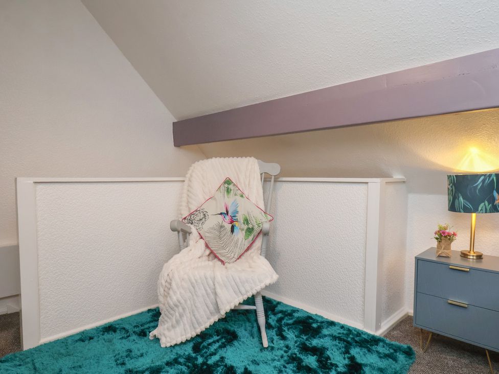 A snug area with a chair and throw blanket at Wayside Farm Cart Cottage in Cloughton near Burniston