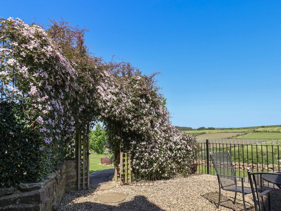 An outdoor area with flowers and a gate at Wayside Farm Cart Cottage Cloughton near Burniston