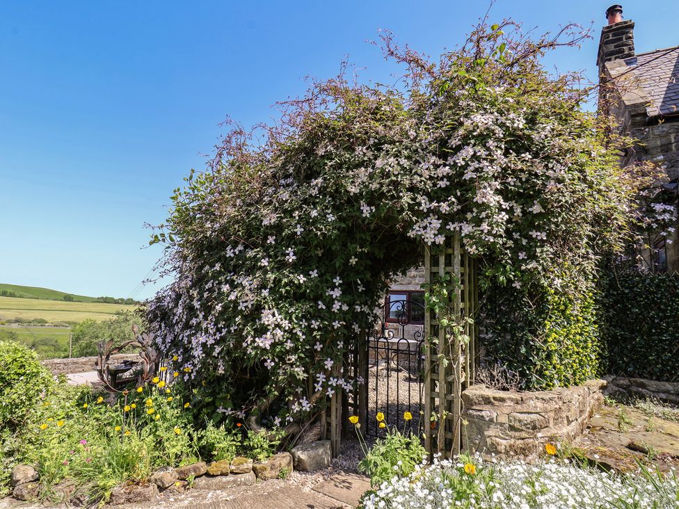 A garden with flowers and a gate at Wayside Farm Cart Cottage in Cloughton near Burniston
