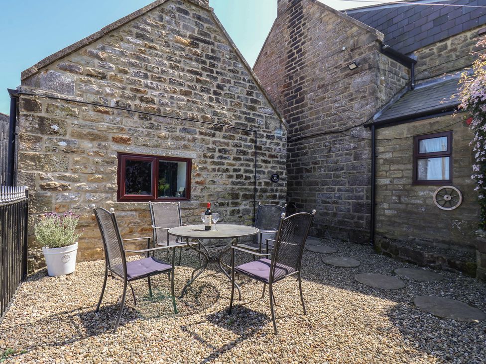 An outdoor area with a table and chairs at Wayside Farm Cart Cottage in Cloughton near Burniston