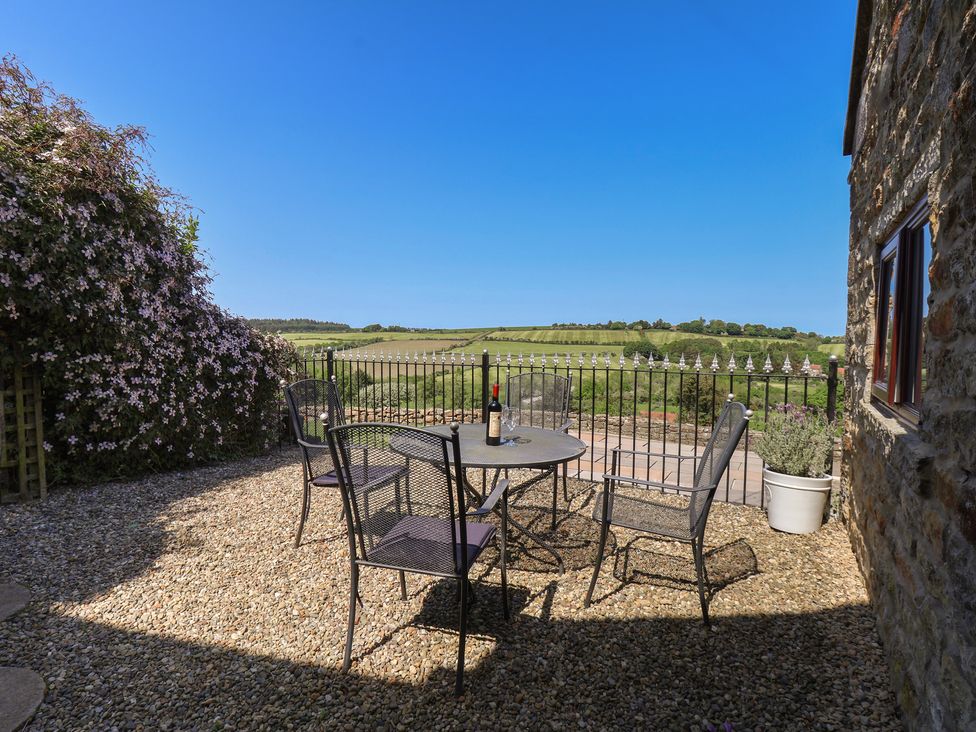 An outdoor patio with a table and chairs at Wayside Farm Cart Cottage in Cloughton near Burniston