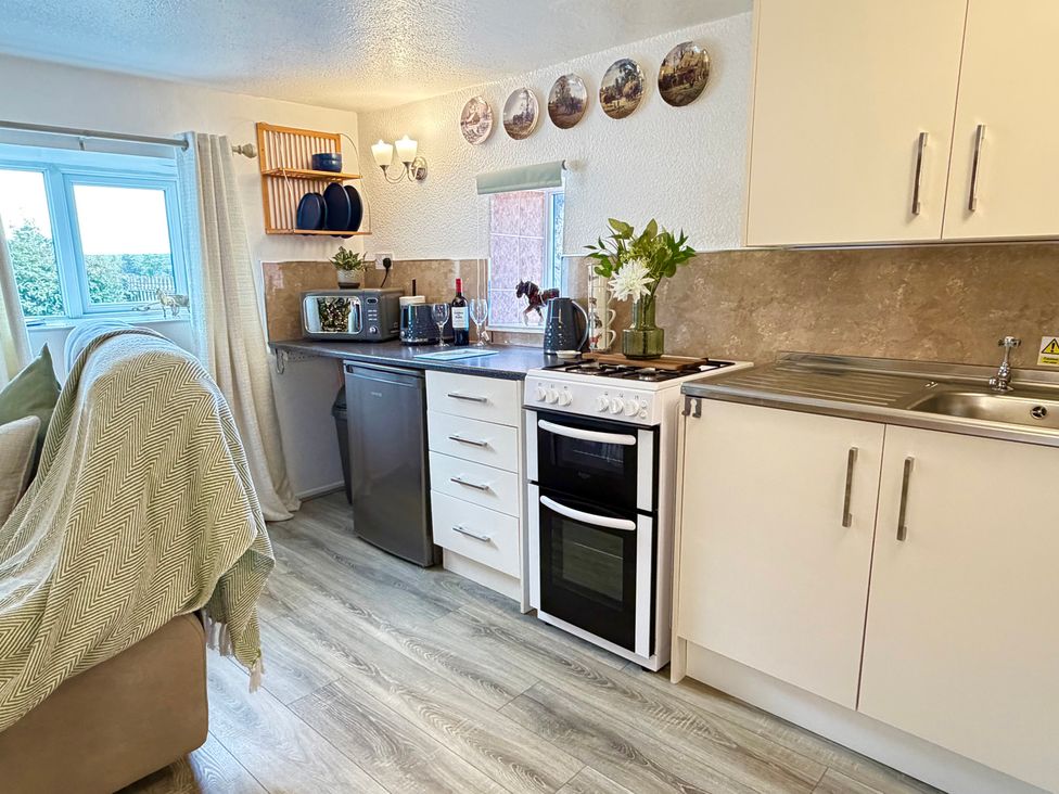 A kitchen with a window, stove, fridge, and sink at Wayside Farm Cart Cottage Cloughton near Burniston