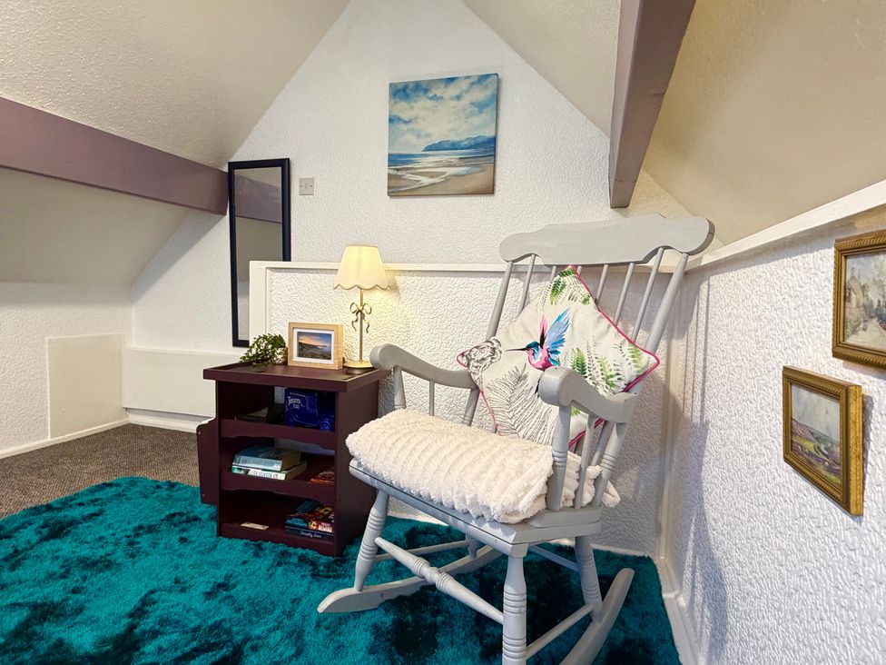 An attic with a rocking chair and small table at Wayside Farm Cart Cottage Cloughton near Burniston