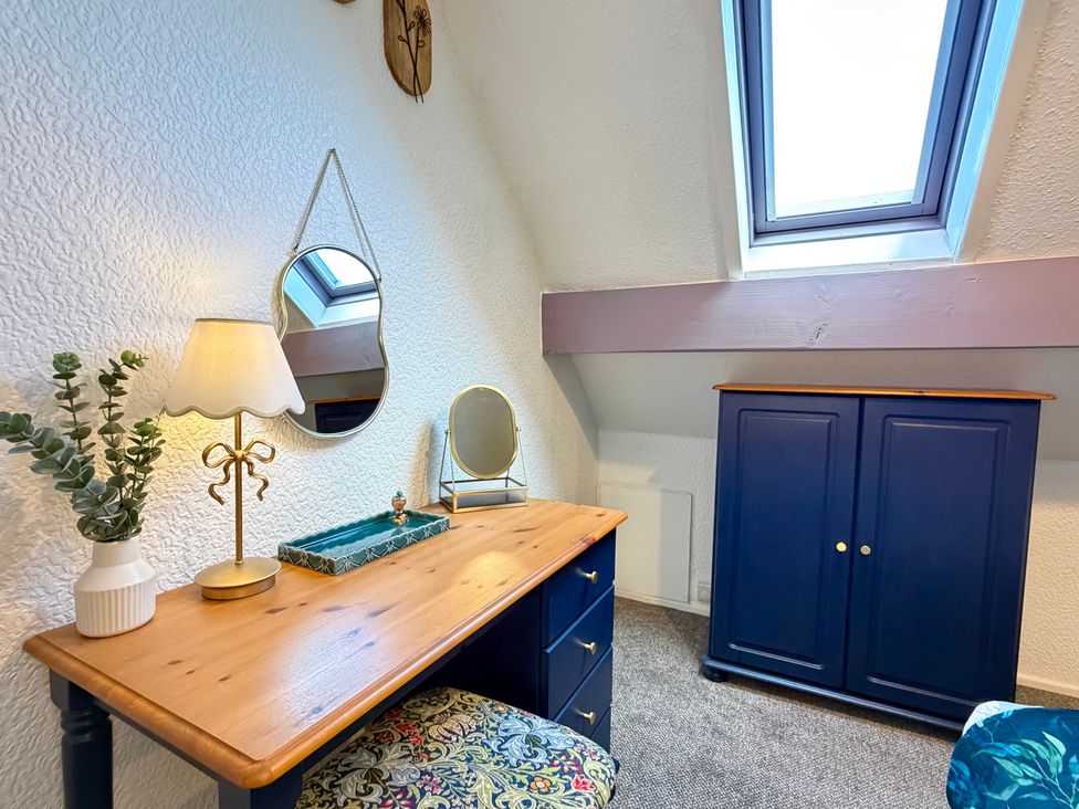 A bedroom with a desk and a lamp at Wayside Farm Cart Cottage Cloughton near Burniston