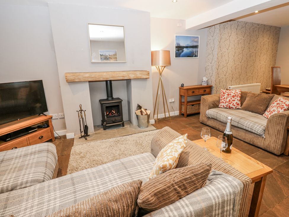 A living room with a fireplace and seating at Mill Race House in Alston